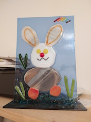 A photo of a piece of glass art with a cartoony rabbit on it.
